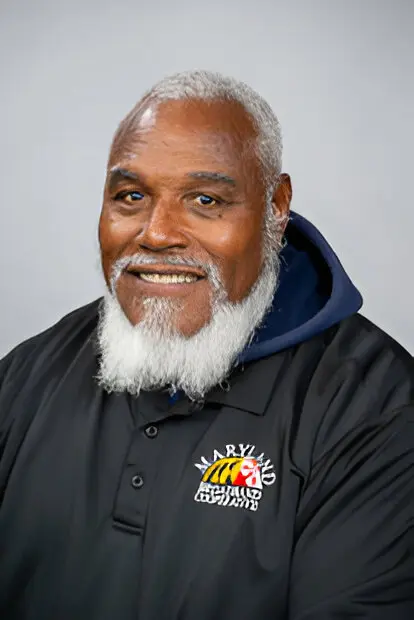 Smiling older man with a white beard wearing a black polo shirt with a Maryland Tigers logo on it, embodying the spirit of community and broadband access for all.