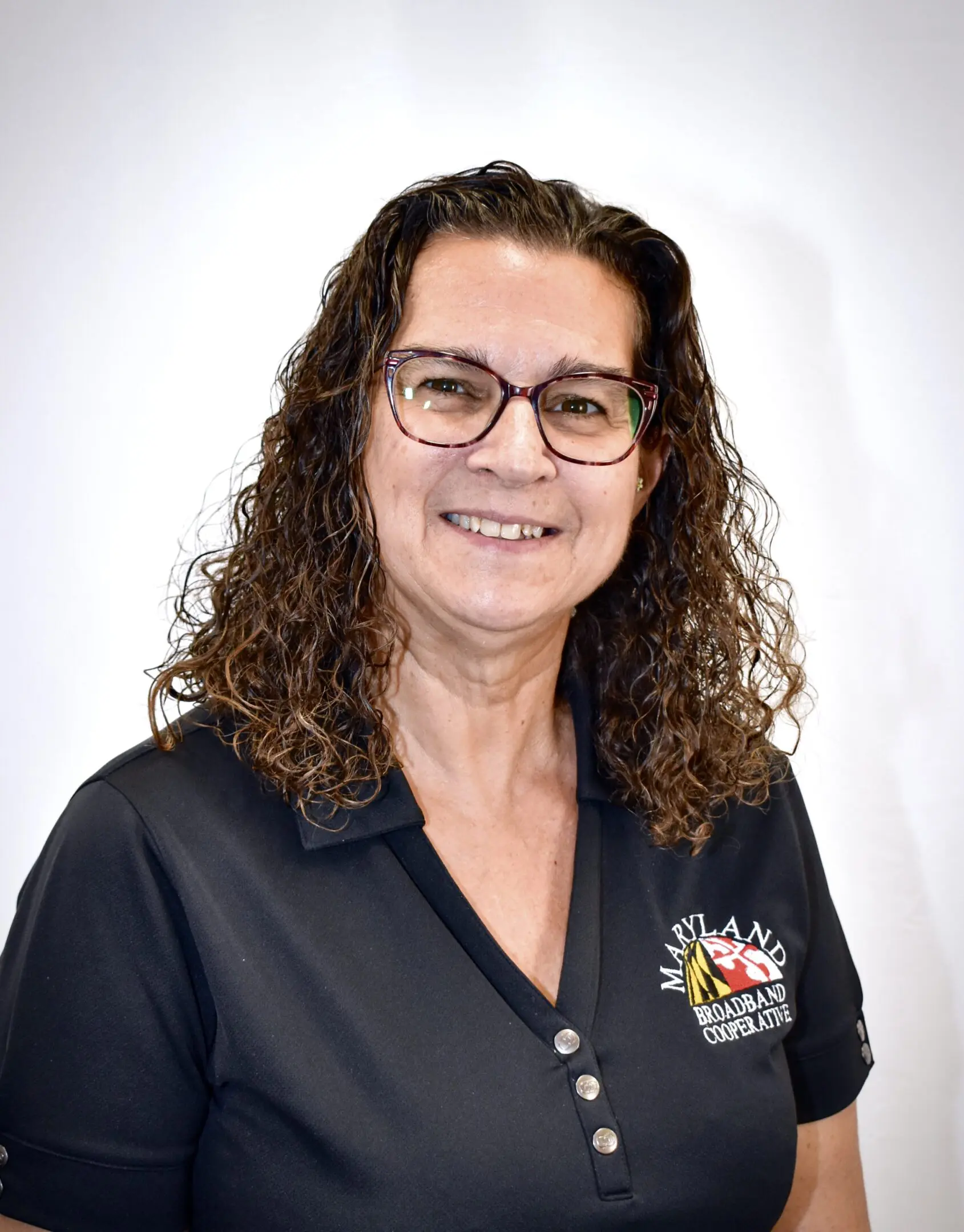 Smiling woman wearing glasses and black polo shirt.