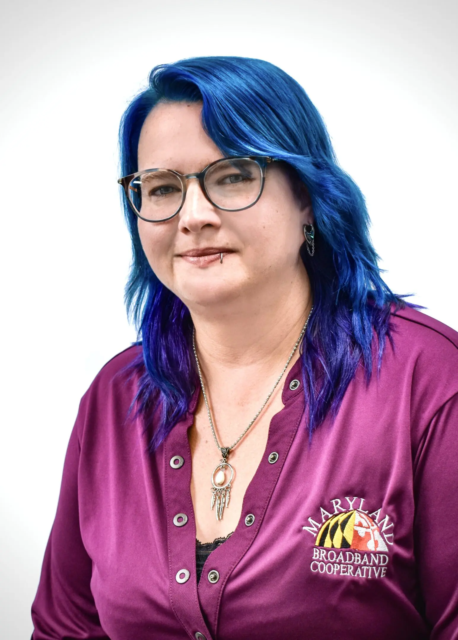 Woman with blue hair, glasses, and MBC shirt.