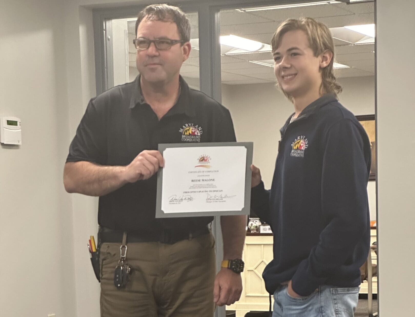 Man presenting certificate to young man.